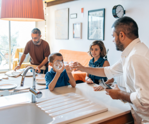 Two male parents setting the table with their adopted son and daughter.