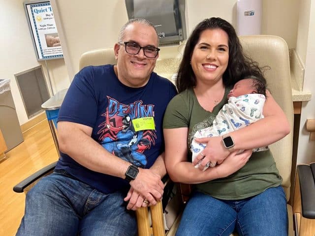 Two parents smiling and holding their adopted newborn. 